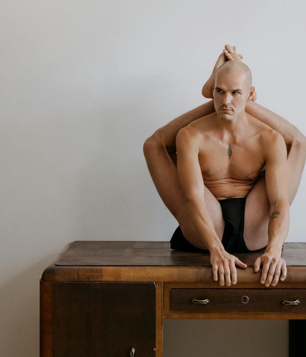 Man in a focused strength pose, demonstrating body control in a minimalist setting.